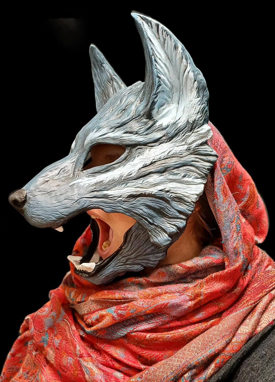 Detail of the piercing eyes and menacing fangs of the realistic wolf mask.