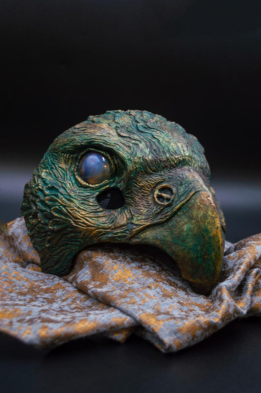 Elegant green and gold Oxidized Hawk mask on a drape, a decorative element that evokes tradition and grandeur.