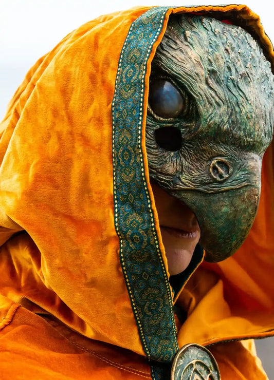 Green medieval-style tunic paired with theater masks for a complete look.