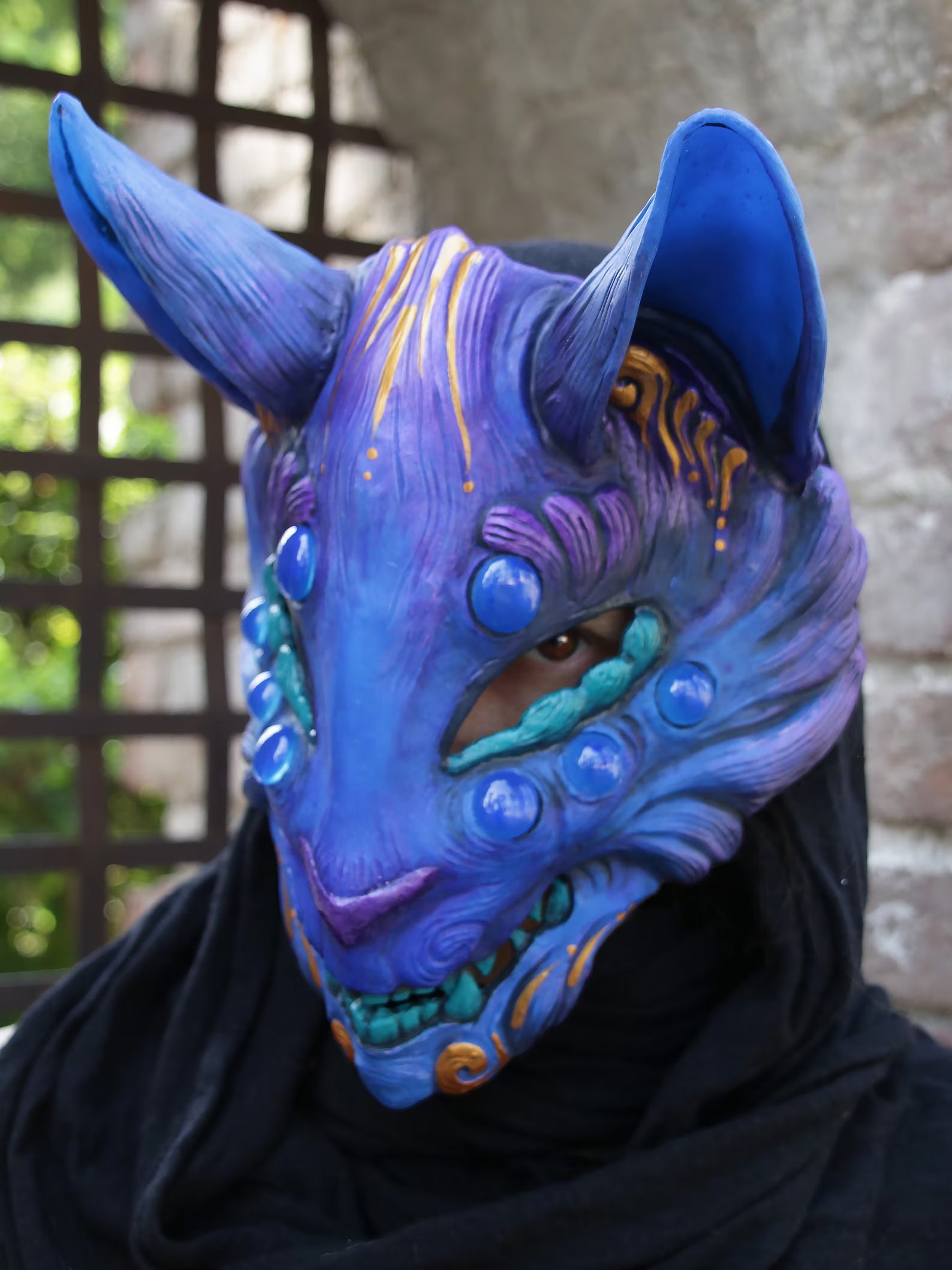 Fluorescent Kitsune mask glowing under UV (black) light.
