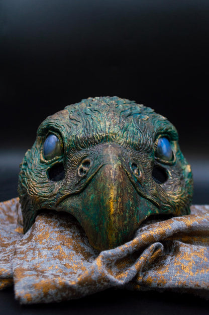 A vibrant Oxidized Hawk with striking blue eyes rests elegantly on a textured cloth
