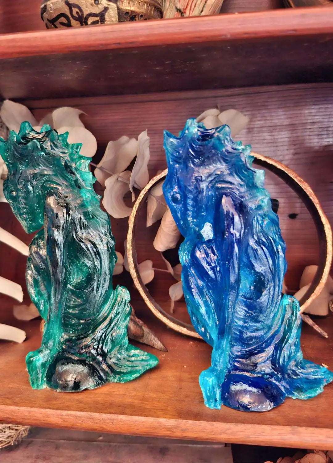 Two translucent ocean-themed Dagon Idol dragon sculptures in deep teal and ocean blue shades displayed inside a curiosity cabinet.