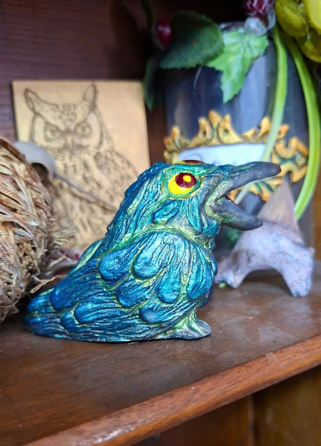 Side view of an emerald green and teal fantasy raven statue with metallic highlights and yellow eyes, suitable for a gothic home interior.