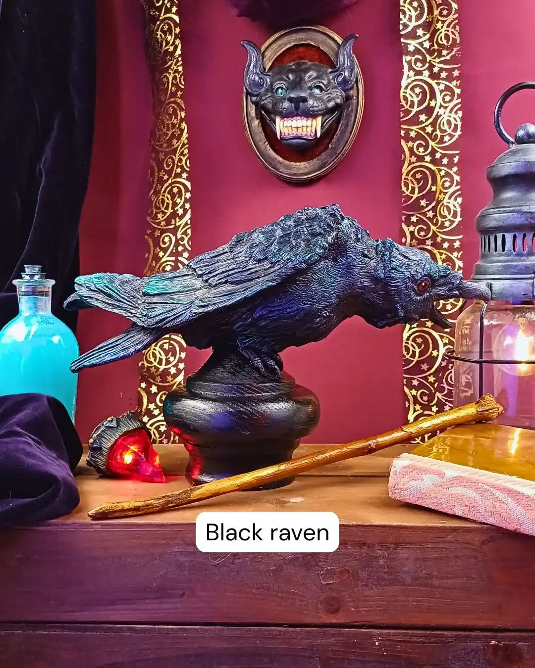 Side view of a sculpted black crow with a dynamic pose, displayed among mystical props and golden gothic wall decor.